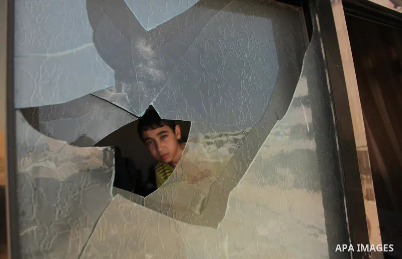 A Palestinian boy is pictured through a window following an air strike by the Israeli airforce on Gaza City, on June 16, 2014. Israel launched air strikes on different areas of on Gaza Strip, as Israeli troops killed a P...