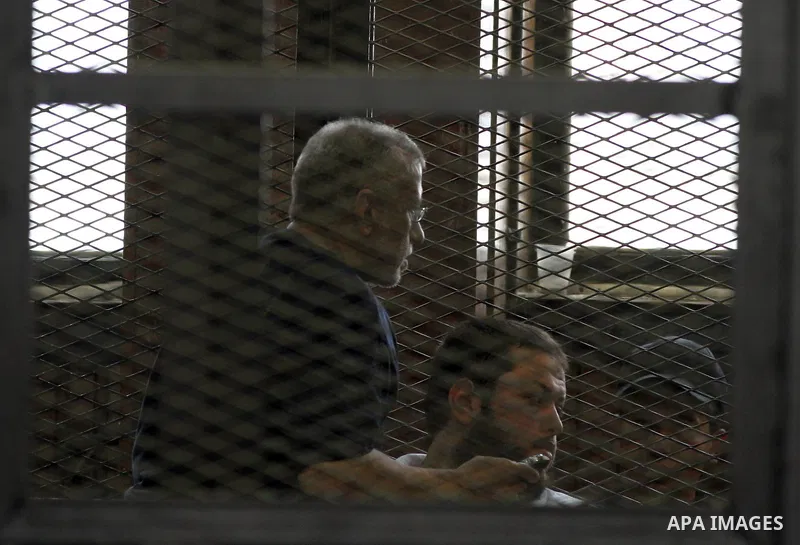 Egyptian Muslim Brotherhood members stand inside the defendants cage during their trial in the capital Cairo on June 17, 2014. The court postponed to July 23 the verdict in the trial of Muslim Brotherhood Supreme Guide M...