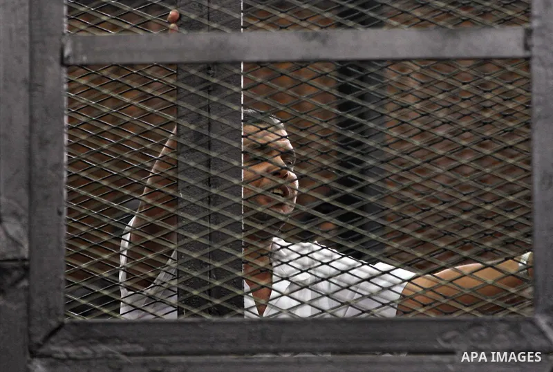 Egyptian Muslim Brotherhood members stand inside the defendants cage during their trial in the capital Cairo on June 17, 2014. The court postponed to July 23 the verdict in the trial of Muslim Brotherhood Supreme Guide M...