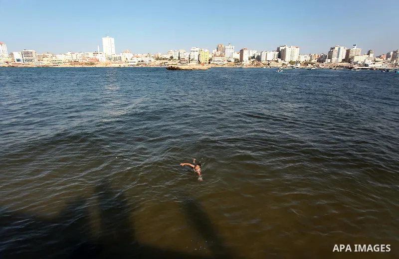 A Palestinian youth enjoys swimming at the beach of Gaza City, on June 17, 2014. Photo by Ashraf Amra