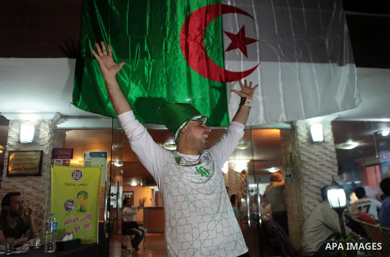 A Palestinian man wears the Algerian football team costume celebrates the first goal of Algerian team as he watches the match between Algeria and Belgium during the 2014 FIFA World Cup in Brazil, on June 17, 2014 in a ca...