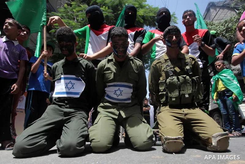 Palestinian Hamas supporters dressed as Israeli soldiers in a scene that alludes to the kidnapping of three Israeli teenagers during a demonstration in solidarity with prisoners held in Israeli jails, and in support of t...