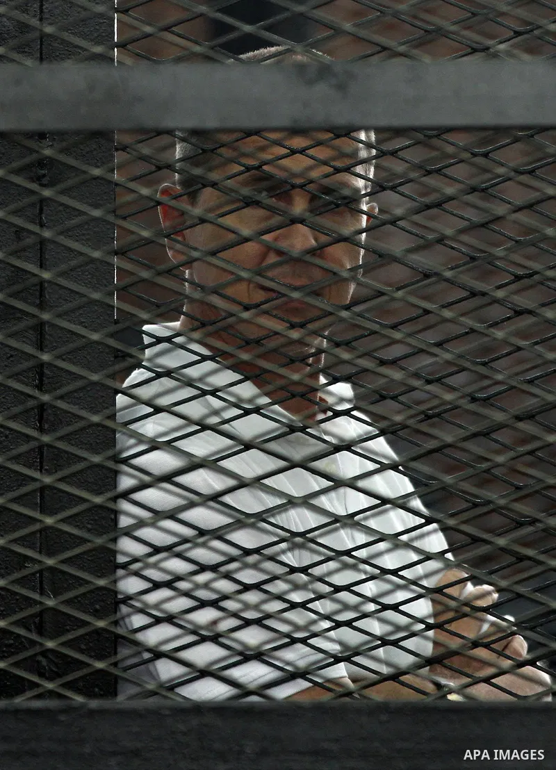 Australian journalist Peter Greste stands inside court's cage as he waits to listen the ruling at a court in Cairo June 23, 2014. Three Al Jazeera journalists were jailed for seven years in Egypt on Monday after a court...