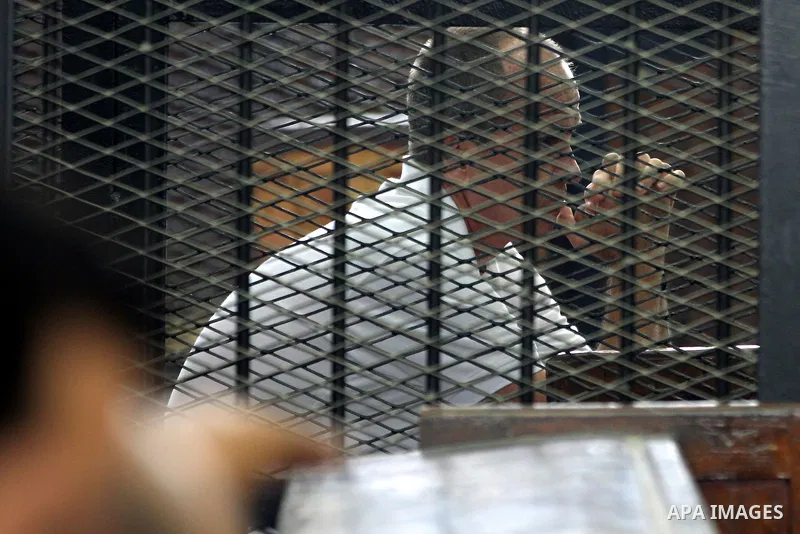 Australian journalist Peter Greste stands inside court's cage as he waits to listen the ruling at a court in Cairo June 23, 2014. Three Al Jazeera journalists were jailed for seven years in Egypt on Monday after a court...