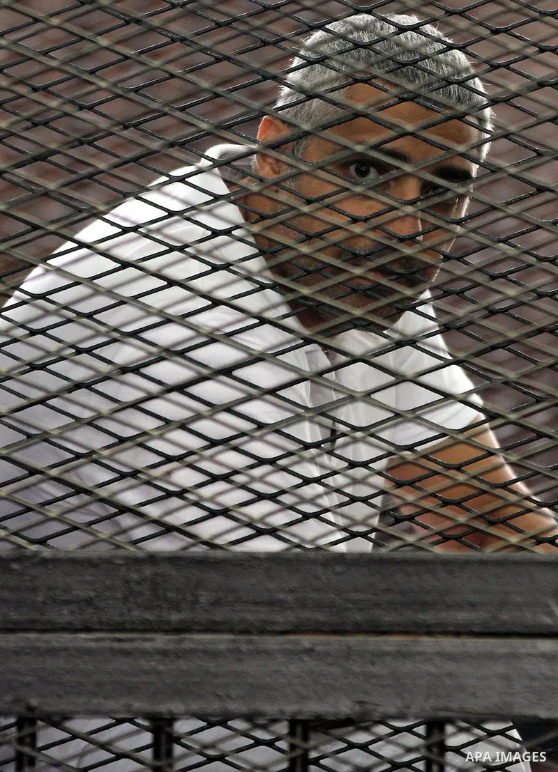 Mohamed Fahmy sits inside court's cage as he waits to listen the ruling at a court in Cairo June 23, 2014. Three Al Jazeera journalists were jailed for seven years in Egypt on Monday after a court convicted them of helpi...