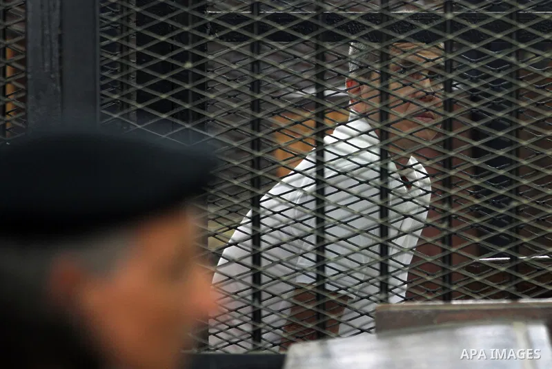 Australian journalist Peter Greste stands inside court's cage as he waits to listen the ruling at a court in Cairo June 23, 2014. Three Al Jazeera journalists were jailed for seven years in Egypt on Monday after a court...