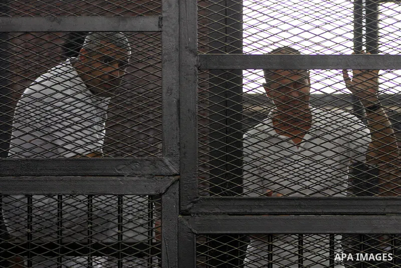 Australian journalist Peter Greste and Mohamed Fahmy stand inside court's cage as he waits to listen the ruling at a court in Cairo June 23, 2014. Three Al Jazeera journalists were jailed for seven years in Egypt on Mond...