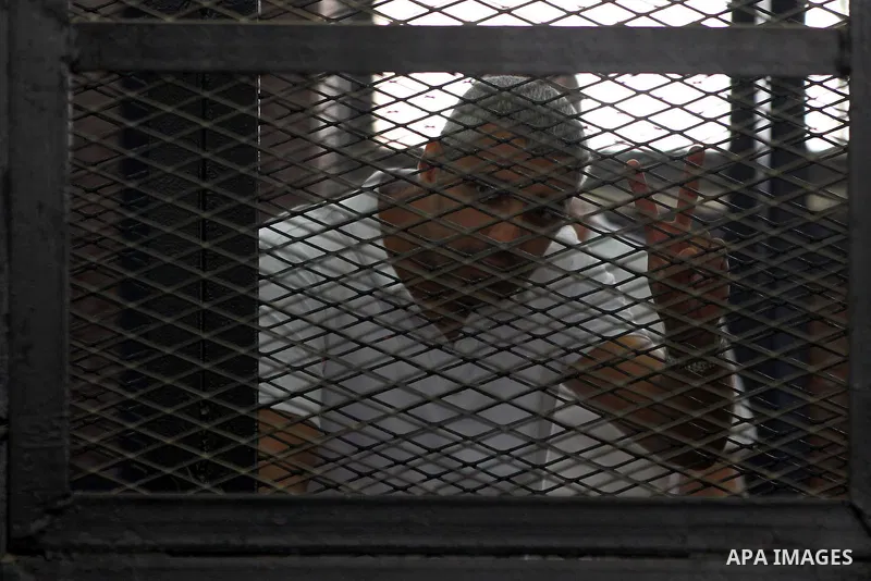 Mohamed Fahmy, stands inside court's cage as he waits to listen the ruling at a court in Cairo June 23, 2014. Three Al Jazeera journalists were jailed for seven years in Egypt on Monday after a court convicted them of he...