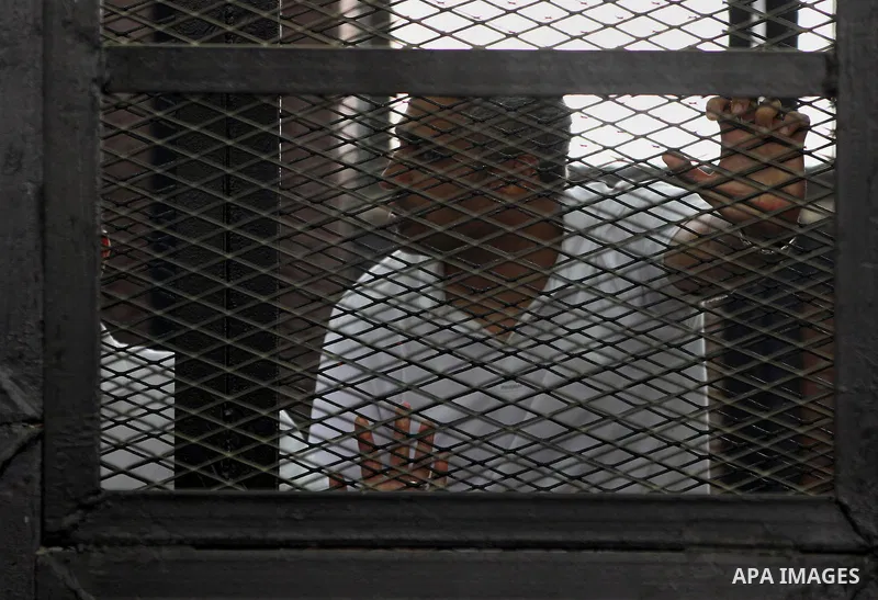 Mohamed Fahmy sits inside court's cage as he waits to listen the ruling at a court in Cairo June 23, 2014. Three Al Jazeera journalists were jailed for seven years in Egypt on Monday after a court convicted them of helpi...