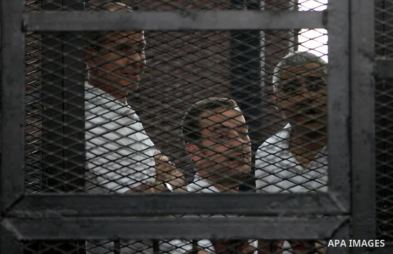 Al-Jazeera journalists stand inside court's cage as their wait to listen the ruling at a court in Cairo June 23, 2014. Three Al Jazeera journalists were jailed for seven years in Egypt on Monday after a court convicted t...