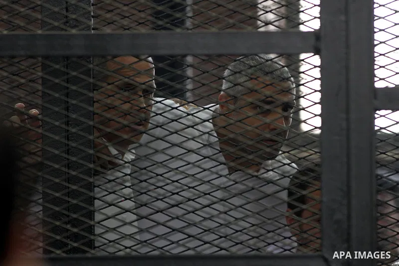 Australian journalist Peter Greste and Mohamed Fahmy stand inside court's cage as he waits to listen the ruling at a court in Cairo June 23, 2014. Three Al Jazeera journalists were jailed for seven years in Egypt on Mond...
