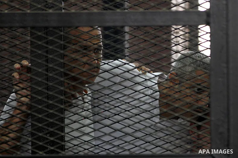Australian journalist Peter Greste and Mohamed Fahmy stand inside court's cage as he waits to listen the ruling at a court in Cairo June 23, 2014. Three Al Jazeera journalists were jailed for seven years in Egypt on Mond...