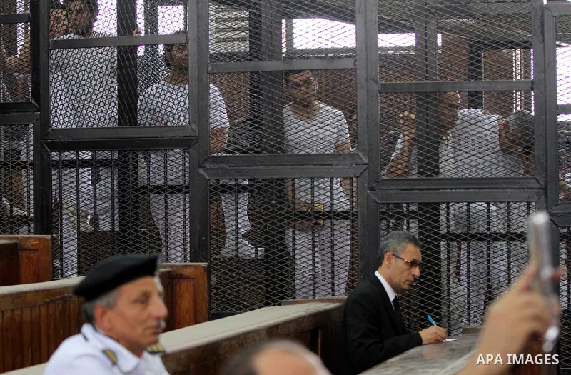 Al-Jazeera journalists stand inside court's cage as their wait to listen the ruling at a court in Cairo June 23, 2014. Three Al Jazeera journalists were jailed for seven years in Egypt on Monday after a court convicted t...