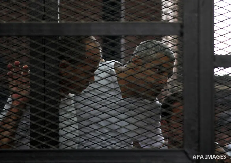 Australian journalist Peter Greste and Mohamed Fahmy stand inside court's cage as he waits to listen the ruling at a court in Cairo June 23, 2014. Three Al Jazeera journalists were jailed for seven years in Egypt on Mond...