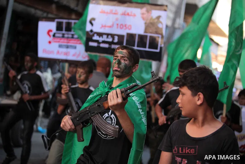 Palestinian children hold weapons and pictures of Gilad Shalit, a former Israel defense forces soldier who was kidnapped by Hamas in 2006, during a rally in solidarity with the hunger-striking Palestinian prisoners held...
