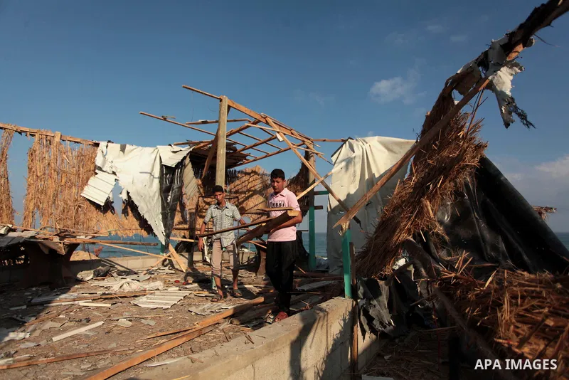 Palestinian men inspect the site of an Israeli air strike in the central Gaza Strip June 25, 2014. Militants in the Gaza Strip, a coastal enclave where Hamas is dominant and has vowed revenge at Israel's crackdown, fired...