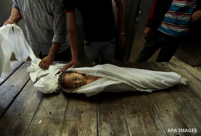 Mourners gather around the body of three-year-old Palestinian girl Jud al-Danaf before her funeral, at a hospital morgue in Gaza City June 25, 2014. The Gaza girl was killed and three of her family were wounded in an exp...