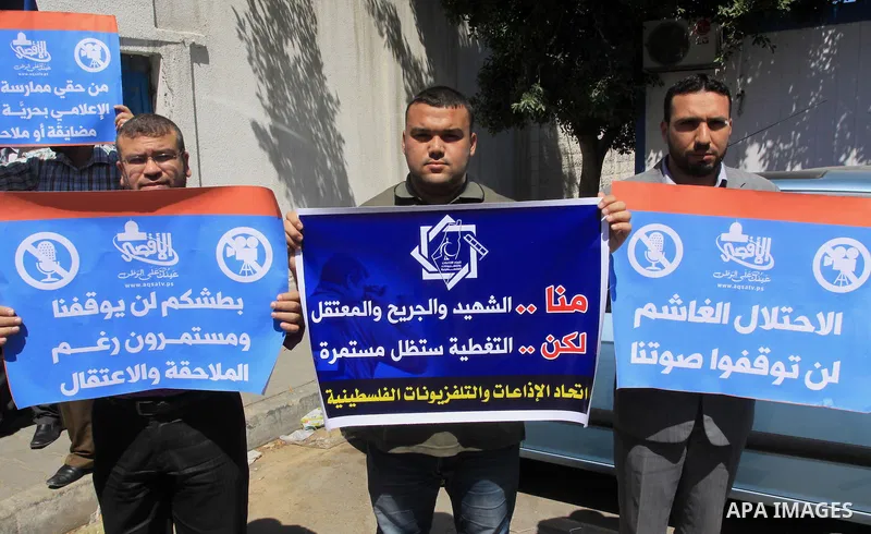 Palestinian journalists hold placards during a protest calling for stop the Israeli violence against journalists in West Bank in front of high commissioner for human rights headquarters, in Gaza City on June 25, 2014. Ph...