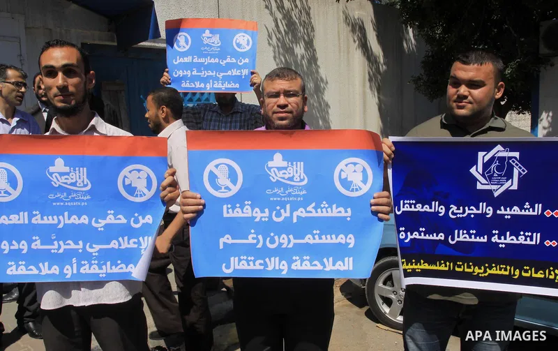 Palestinian journalists hold placards during a protest calling for stop the Israeli violence against journalists in West Bank in front of high commissioner for human rights headquarters, in Gaza City on June 25, 2014. Ph...