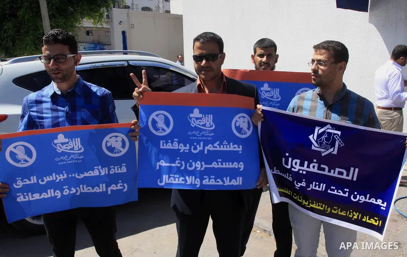 Palestinian journalists hold placards during a protest calling for stop the Israeli violence against journalists in West Bank in front of high commissioner for human rights headquarters, in Gaza City on June 25, 2014. Ph...