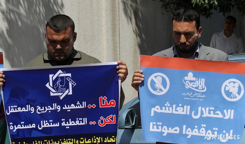 Palestinian journalists hold placards during a protest calling for stop the Israeli violence against journalists in West Bank in front of high commissioner for human rights headquarters, in Gaza City on June 25, 2014. Ph...