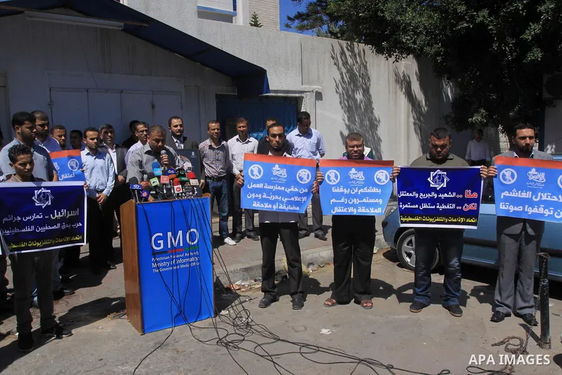 Palestinian journalists hold placards during a protest calling for stop the Israeli violence against journalists in West Bank in front of high commissioner for human rights headquarters, in Gaza City on June 25, 2014. Ph...