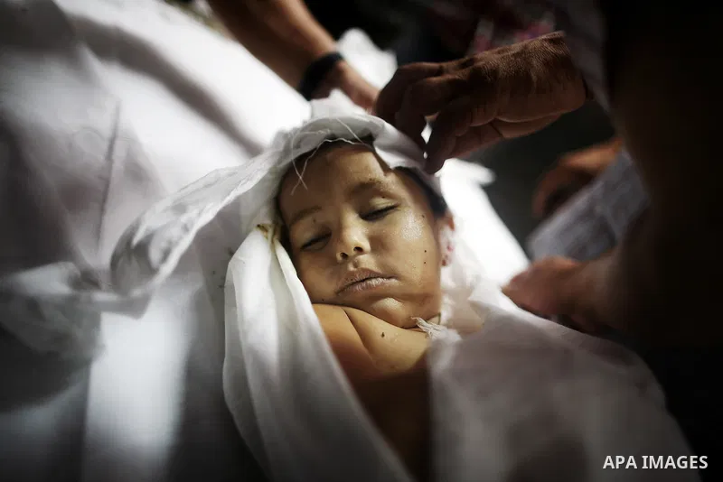 Mourners gather around the body of three-year-old Palestinian girl Jud al-Danaf before her funeral, at a hospital morgue in Gaza City June 25, 2014. The Gaza girl was killed and three of her family were wounded in an exp...