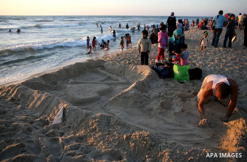 Palestinians enjoy a day on the beach in the central Gaza Strip June 26, 2014. Palestinian Environment Quality Authority said in a statement the pollution of the seawater has gone beyond 50 percent. The lack of enough fu...