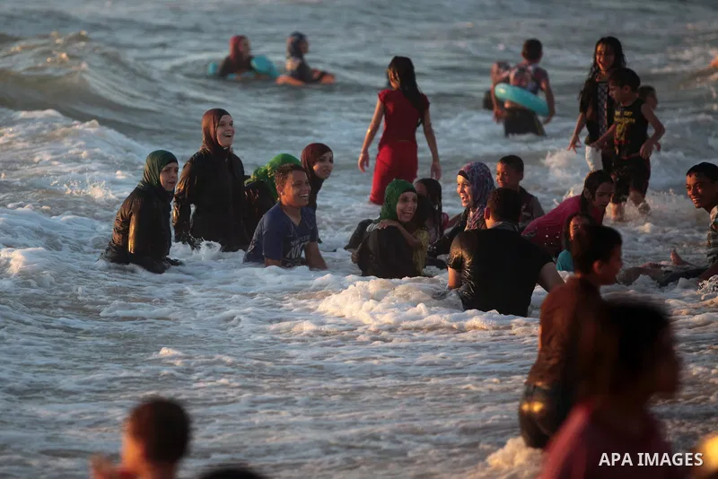 Palestinians enjoy a day on the beach in the central Gaza Strip June 26, 2014. Palestinian Environment Quality Authority said in a statement the pollution of the seawater has gone beyond 50 percent. The lack of enough fu...