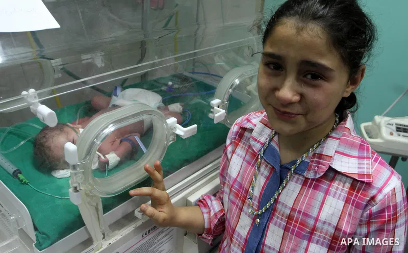 Aseel Khadoora, the daughter of Palestinian prisoner Saleh Khadoora, stands near her new brother as he lies in an incubator at a hospital, in Gaza City on June 26, 2014. The wife of Palestinian jailed in Israel Saleh Kha...