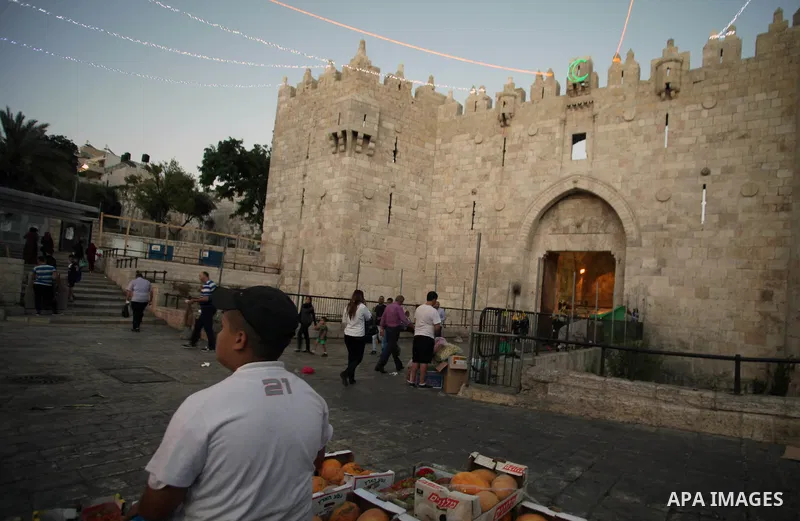 People walk under lights decorating Damascus Gate outside the old city of Jerusalem on June 26, 2014, as Muslims prepare for the upcoming holy fasting month of Ramadan. Muslims around the world celebrate Ramadan, the hol...