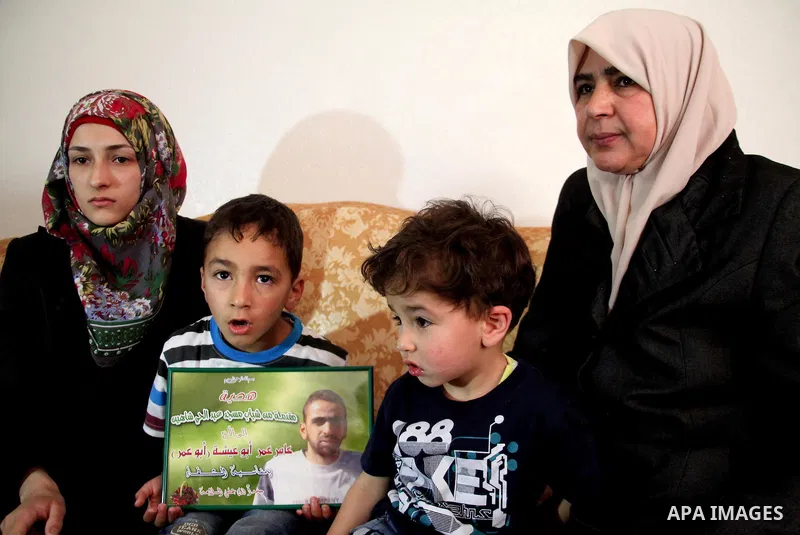 The son of Amer Abu Aysha holds his father's picture as he poses with his grandmother (R), his brother and his mother for media in their house in the West Bank city of Hebron June 27, 2014. Israel on Thursday named Abu A...