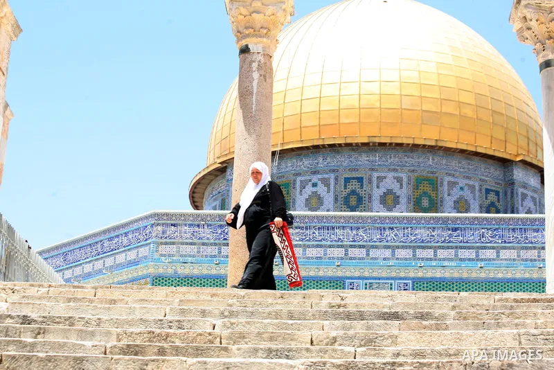 A Palestinian woman walks in front of the Dome of the Rock mosque following Friday prayers at the Al-Aqsa mosque compound, Islam's third holiest site, in the Old City of Jerusalem on June 27, 2014. Photo by Saeed Qaq