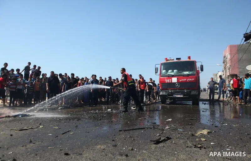 Firefighters wash the debris of a car that was targeted by an Israeli air strike in Gaza City on June 27, 2014. The air strike killed two Palestinians, medics said, hours after a bomb exploded near troops manning Israel'...