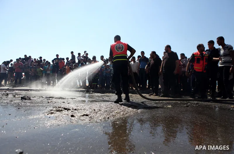 Firefighters wash the debris of a car that was targeted by an Israeli air strike in Gaza City on June 27, 2014. The air strike killed two Palestinians, medics said, hours after a bomb exploded near troops manning Israel'...