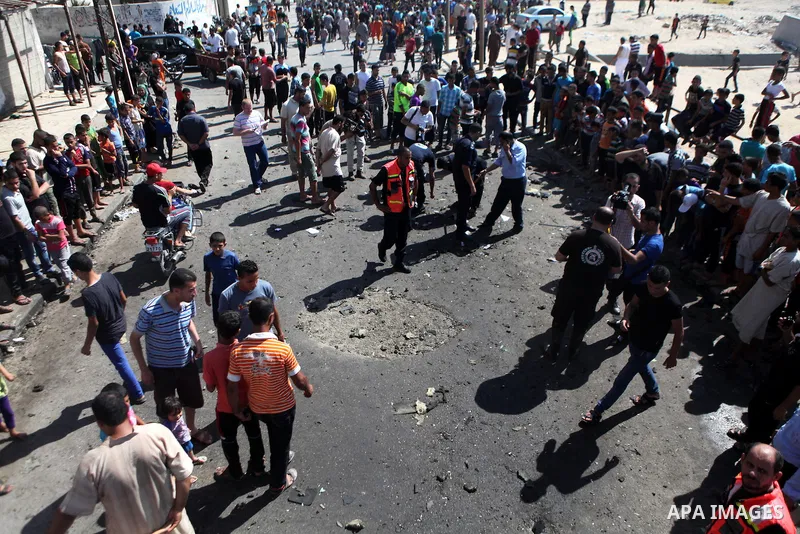 Palestinians inspect the site of an Israeli air strike after targeting a car in Gaza City on June 27, 2014. The air strike killed two Palestinians, medics said, hours after a bomb exploded near troops manning Israel's se...