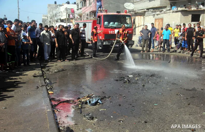 Firefighters wash the debris of a car that was targeted by an Israeli air strike in Gaza City on June 27, 2014. The air strike killed two Palestinians, medics said, hours after a bomb exploded near troops manning Israel'...
