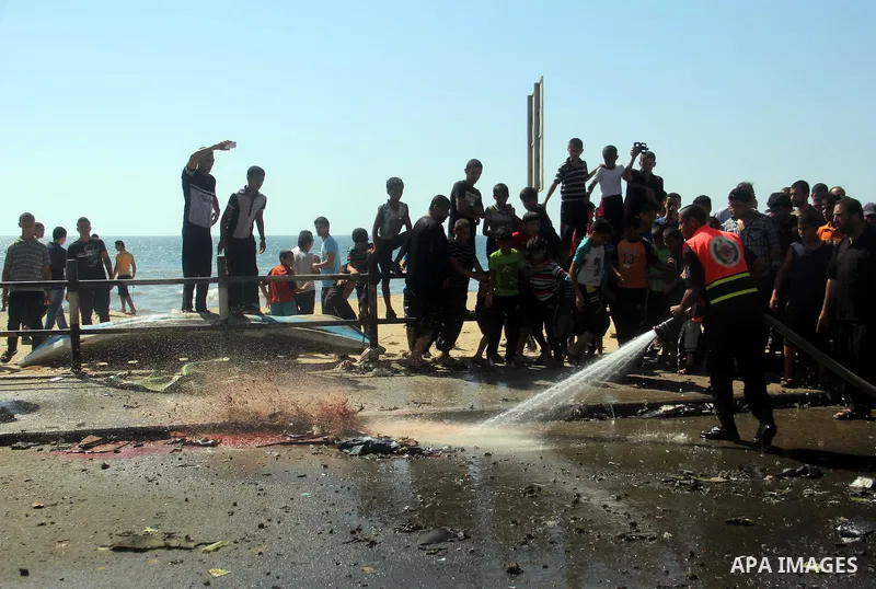 Firefighters wash the debris of a car that was targeted by an Israeli air strike in Gaza City on June 27, 2014. The air strike killed two Palestinians, medics said, hours after a bomb exploded near troops manning Israel'...