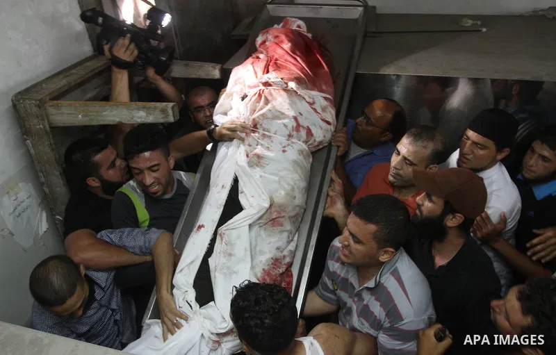 Palestinians mourn around the body of a Palestinian militant at a hospital morgue in Gaza City June 27, 2014. An Israeli air strike killed two Palestinian militants and critically wounded a third in the Gaza Strip on Fri...