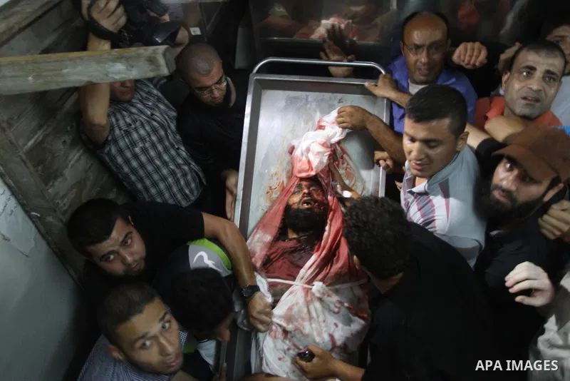 Palestinians mourn around the body of a Palestinian militant at a hospital morgue in Gaza City June 27, 2014. An Israeli air strike killed two Palestinian militants and critically wounded a third in the Gaza Strip on Fri...