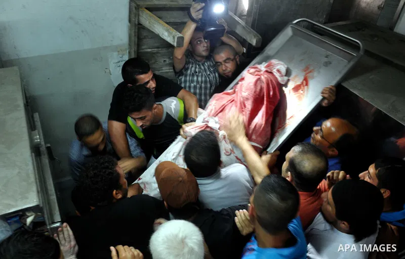 Palestinians mourn around the body of a Palestinian militants at a hospital morgue in Gaza City June 27, 2014. An Israeli air strike killed two Palestinian militants and critically wounded a third in the Gaza Strip on Fr...