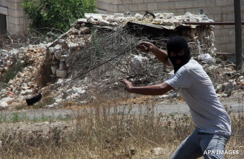 A Palestinian protester hurls stones towards Israeli security forces during clashes following a weekly protest against the expropriation of Palestinian land by Israel in the West Bank village of Kfar Qaddum, near Nablus...