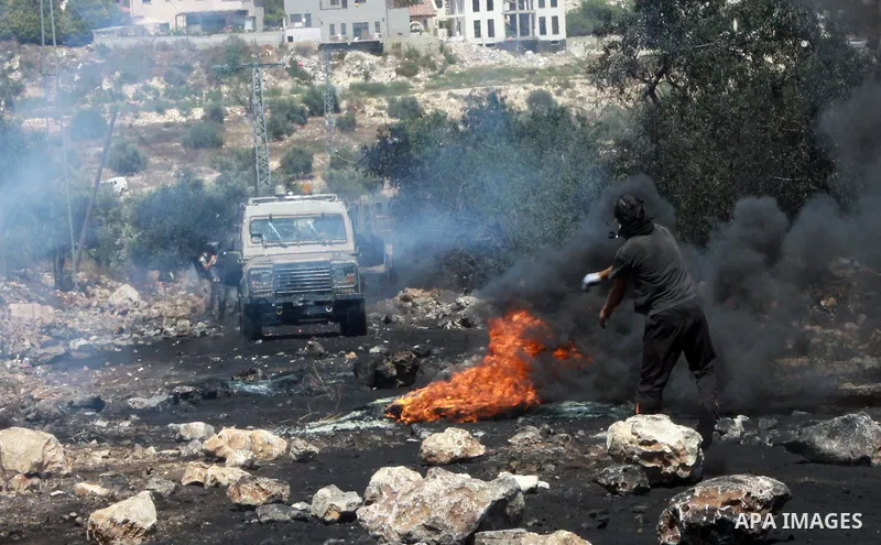 A Palestinian protester throws stones towards Israeli security forces during clashes following a weekly protest against the expropriation of Palestinian land by Israel in the West Bank village of Kfar Qaddum, near Nablus...
