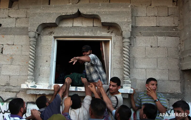 Mourners prepare to carry the body of Palestinian militant Osama al-Hosomi through the window of his family's house during his funeral in the northern Gaza Strip June 27, 2014. An Israeli air strike killed two Palestinia...