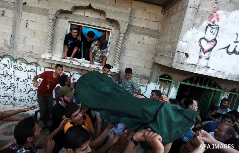 Mourners prepare to carry the body of Palestinian militant Osama al-Hosomi through the window of his family's house during his funeral in the northern Gaza Strip June 27, 2014. An Israeli air strike killed two Palestinia...