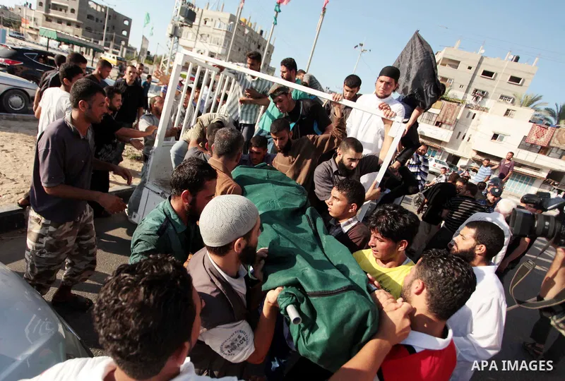 Mourners prepare to carry the body of Palestinian militant Osama al-Hosomi during his funeral in the northern Gaza Strip June 27, 2014. An Israeli air strike killed two Palestinian militants, one of them al-Hosomi, and c...