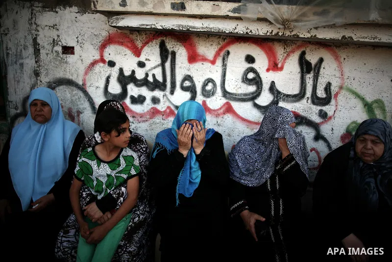 Palestinian relatives of Osama al-Hosomi mourn during his funeral outside his family's house in the northern Gaza Strip June 27, 2014. An Israeli air strike killed two Palestinian militants, one of them al-Hosomi, and cr...
