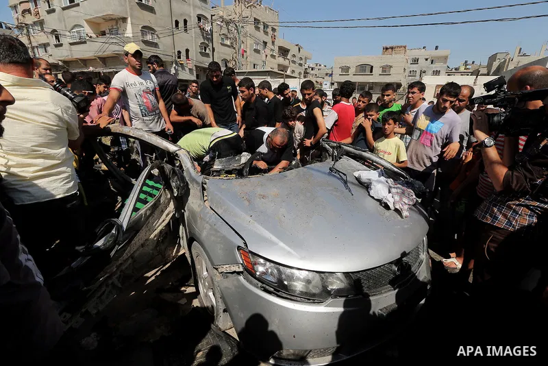 Palestinians inspect a car that was targeted in an Israeli air strike in Gaza City on June 27, 2014. An Israeli air strike killed two Palestinian militants and critically wounded a third in the Gaza Strip on Friday, the...