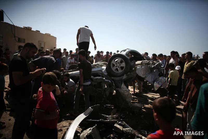 Palestinians inspect a car that was targeted in an Israeli air strike in Gaza City on June 27, 2014. An Israeli air strike killed two Palestinian militants and critically wounded a third in the Gaza Strip on Friday, the...