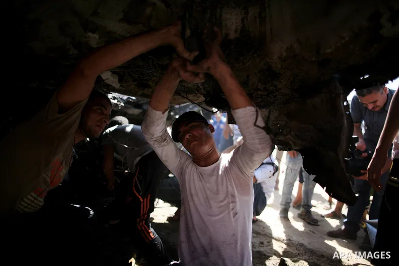 Palestinians inspect a car that was targeted in an Israeli air strike in Gaza City on June 27, 2014. An Israeli air strike killed two Palestinian militants and critically wounded a third in the Gaza Strip on Friday, the...